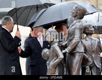 31. März 2023, Hamburg: König Karl III. (2. von links) von Großbritannien und seine Frau stehen gemeinsam mit dem deutschen Präsidenten Steinmeier (nicht im Bild) und seiner Frau Elke Büdenbender (M) vor dem Denkmal "Kindertransport - der letzte Abschied" (Kindertransport - der letzte Abschied) am Bahnhof Dammtor. Die Bronzeskulptur erinnert vor allem an jüdische Kinder, die während der Nazi-Ära nach Großbritannien geschickt wurden und ihre Verwandten, die zurückblieben, meist nie wieder sahen. Am Ende ihrer dreitägigen Reise nach Deutschland besuchen der britische König und seine Frau die Hansestadt Hamburg. Stockfoto