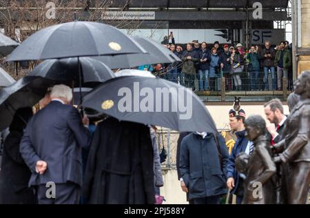 Hamburg, Deutschland. 31. März 2023. Königliche Fans sehen König Karl III. Von Großbritannien (verschleiert) und den deutschen Präsidenten Frank-Walter Steinmeier (l) auf der Gedenkstätte "Kindertransport - der letzte Abschied". Die Bronzeskulptur erinnert vorwiegend an jüdische Kinder, die während der Nazi-Ära nach Großbritannien geschickt wurden, von denen die meisten ihre Verwandten nie wieder gesehen haben, die zurückblieben. Am Ende ihrer dreitägigen Reise nach Deutschland besuchen der britische König und seine Frau die Hansestadt Hamburg. Kredit: Jens Büttner/dpa/Alamy Live News Stockfoto