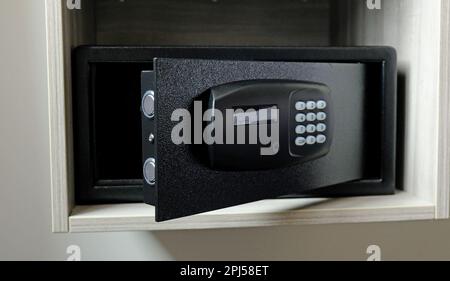 Metallsafe im Schrank. Kleiner, schmaler Safe, in dem man Geld oder Wertsachen im Hotel aufbewahren kann. Öffnen Sie die sichere Tür mit Tasten zur Passworteingabe. Stockfoto