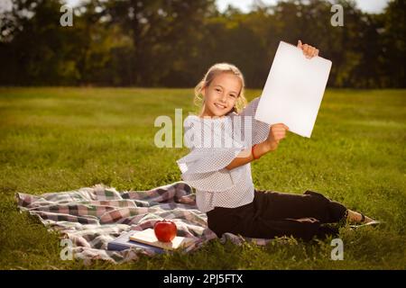 Teenager mit sauberem, weißem Papier im Park im Sommercamp. Willkommen bei der Meisterklasse Kunst zeichnen Stockfoto
