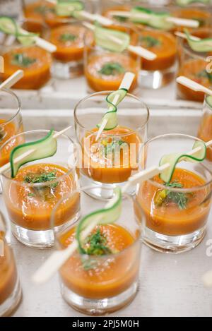 Ein weißes Tablett mit Gläsern heißer, dampfender Suppe, jedes mit Gurkenscheiben garniert Stockfoto