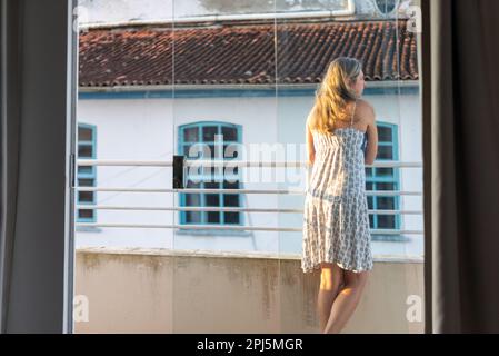 Schöne Frau auf der Veranda des Hauses. Im Hintergrund eine Kirche. Stockfoto