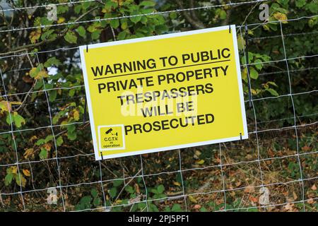 Ein Schild mit der Aufschrift „Warnung vor öffentlichem, privatem Eigentum, Eindringlinge werden strafrechtlich verfolgt“ und „CCTV in Betrieb“, England, Großbritannien Stockfoto