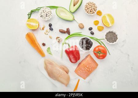 Gesunde FODMAP-Diät in Herzform. Ökologisches Obst, Gemüse, Fleischlachs, Grünzeug, Nüsse, Bohnen, Chiasamen, Oliven. Stockfoto