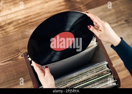 Vinyl-Schallplatten spielen. Musik von einem Vinyl-Plattenspieler hören. Retro- und Vintage-Musikstil. Frau mit analogem LP-Plattenalbum. Stapel alt Stockfoto