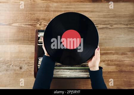 Vinyl-Schallplatten spielen. Musik von einem Vinyl-Plattenspieler hören. Retro- und Vintage-Musikstil. Frau mit analogem LP-Plattenalbum. Stapel alt Stockfoto