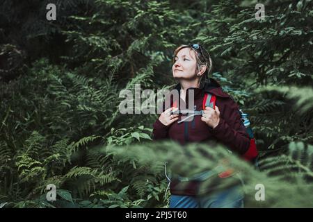 Frau mit Rucksack Wandern im Wald, aktiv verbringen Sommerurlaub in der Nähe der Natur. Frau, die auf einem Pfad zwischen Bäumen läuft Stockfoto