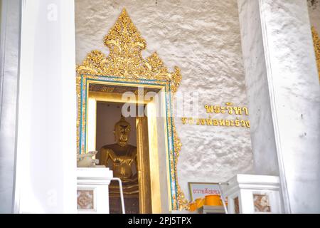 Eine goldene Tür, dekoriert mit Details, wo hinter einer goldenen Buddha-Figur steht am Wat Mahannapharam Worawihan Tempel in Bangkok, Thailand. Stockfoto