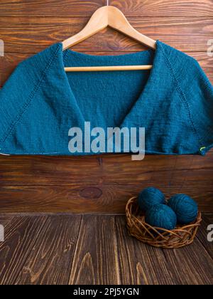Handgefertigter Pullover. Strickmaterial aus grünem Faden auf braunem Hintergrund.Bereich kopieren Stockfoto