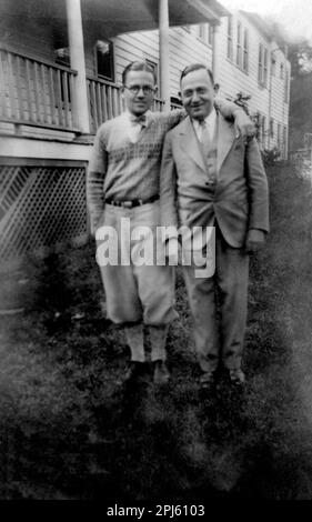 Ca. 1930-1940: 2 Männer stehen draußen, einer trägt Slips. Stockfoto