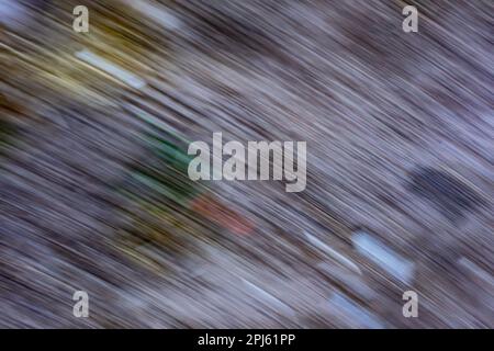 Abstrakte Textur mit sich bewegenden weißgrauen Linien und kleinen Farbschattierungen von Gelb, Orange, Grün und Schwarz im Hintergrund. Der Begriff der Nichteinhaltung Stockfoto