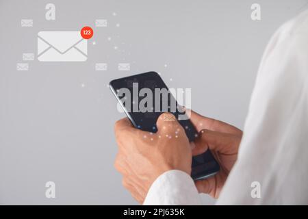 Ein Geschäftsmann, der ein Smartphone mit einem E-Mail-Symbol verwendet. Kommunikationskonzept. Stockfoto