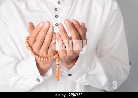 Die Hand eines muslimischen Mannes, der tasbische Perlen hält Stockfoto