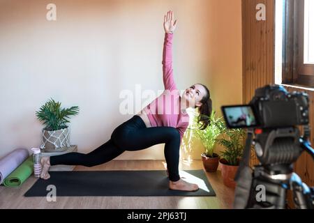 Fitnesstrainer, der Yoga macht und einen gesunden Lebensstil-Vlog aufzeichnet. Stockfoto