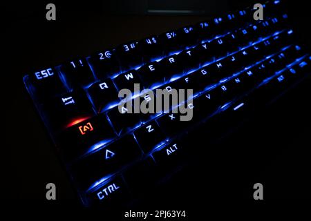 Beleuchtete RGB-Gaming-Tastatur mit Hintergrundbeleuchtung und roter Feststelltaste Stockfoto