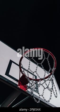 Ein vertikales Bild eines Basketballkörpers im Freien gegen den Nachthimmel Stockfoto