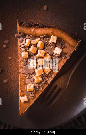 Schokoladenkäsekuchen mit gesalzenem Karamell auf dunklem Hintergrund Stockfoto