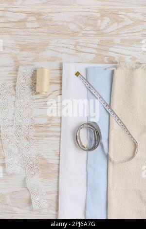 Nähwerkzeuge und Zubehör - Stoff und Zentimeter mit Gewinde auf Holztisch Stockfoto