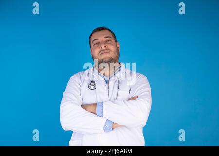 Jugendliches Erwachsenenarztporträt von vorne auf isoliertem blauem Hintergrund. Arztbesuchkonzept Stockfoto