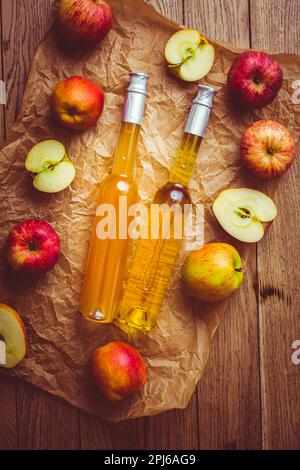 Apfelsaft mit Apfelessig in Flaschen und frischen Äpfeln Auf Holzhintergrund Stockfoto