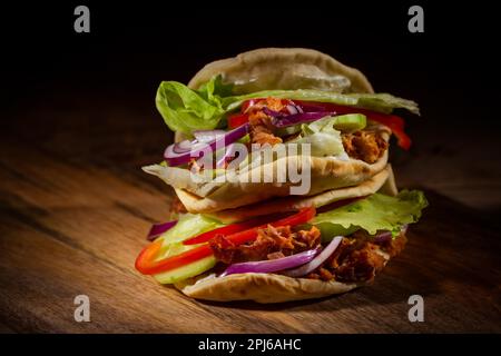 Hausgemachtes Fladenbrot-Sandwich, Kebab oder Döner mit Hühnerfleisch, Salat und Gemüse auf Holzboden Stockfoto