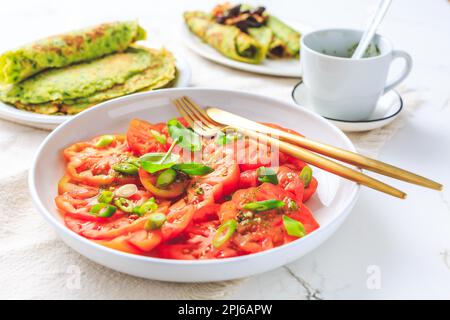 Tomatensalat mit Zwiebeln und Ramson-Pfannkuchen oder Crepes Weißer Hintergrund Stockfoto