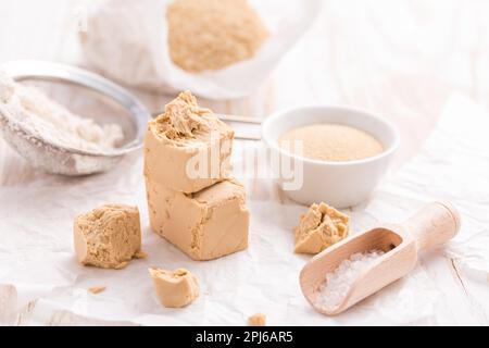 Frische und getrocknete Hefe mit Backzutaten auf weißem Hintergrund Stockfoto