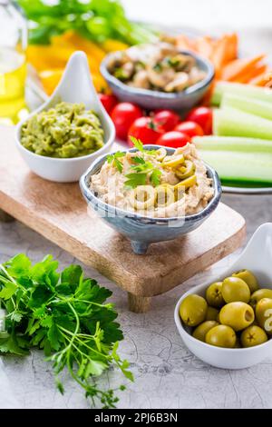 Hausgemachter Hummus und Avocado Dip mit frischem Gemüse und marinierten Pilzen als gesunden Snack Stockfoto