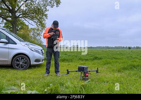 Rettungsteam, das eine professionelle Drohne betreibt, um im Gras verborgene Reh-Rasenmäher mit einer Wärmebildkamera zu lokalisieren, bevor im Frühjahr Gras gemäht wird Stockfoto