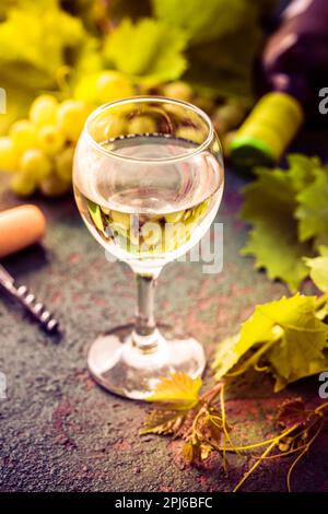 Weißwein und Trauben in altem Ambiente mit Flaschenöffner auf dem Küchentisch Stockfoto