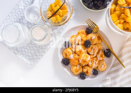 Holländische Mini-Pfannkuchen genannt Poffertjes mit Brombeeren und Apfelkompott Stockfoto