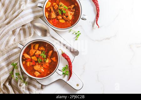 Rindergulaschsuppe – herzhafte ungarische Suppe mit Fleisch und Gemüse, gewürzt mit Paprika auf weißem Hintergrund Stockfoto