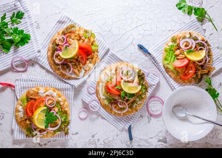 Griechisches Gyros-Fleisch mit Pita-Fladenbrot, Gemüse und Zwiebeln und Tzatziki-Dip auf weißem Hintergrund Stockfoto
