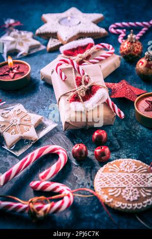 Weihnachtsgeschenke mit Schachteln, Kerzen und Lebkuchenkuchen auf dunkelblauem Hintergrund Stockfoto