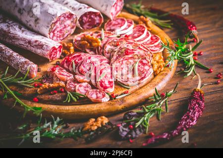 Charcuterie - Sortiment von luftgetrockneten Salami und Wurst auf Holz Schneidebrett mit Gewürzen Stockfoto