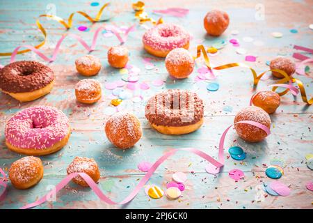 Krapfen, Berliner und Donuts mit Luftschlangen und Konfetti. Farbenfrohes Bild von Karneval, Geburtstag und Fasching Stockfoto