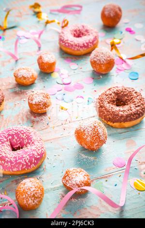Krapfen, Berliner und Donuts mit Luftschlangen und Konfetti. Farbenfrohes Bild von Karneval, Geburtstag und Fasching Stockfoto