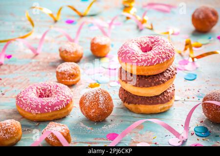 Krapfen, Berliner und Donuts mit Luftschlangen und Konfetti. Farbenfrohes Bild von Karneval, Geburtstag und Fasching Stockfoto