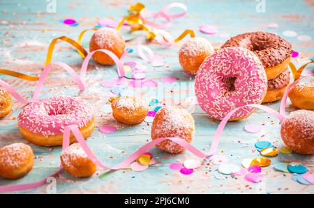 Krapfen, Berliner und Donuts mit Luftschlangen und Konfetti. Farbenfrohes Bild von Karneval, Geburtstag und Fasching Stockfoto