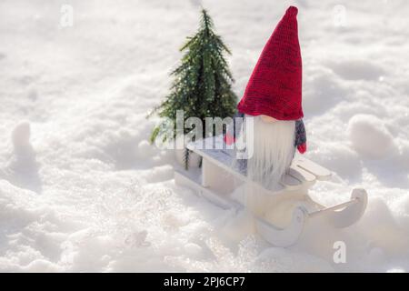 Weihnachtsgeist auf Schlitten mit Baum auf verschneiter Landschaft. Weihnachtsdekoration Stockfoto
