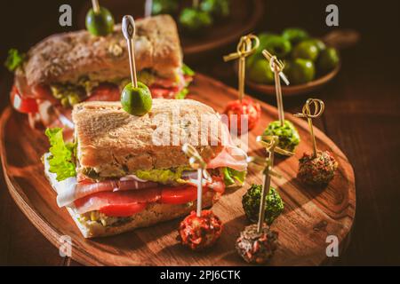 Hausgemachtes Ciabatta-Sandwich mit Guacamole, Prosciutto, Salat, Tomaten und Oliven Stockfoto