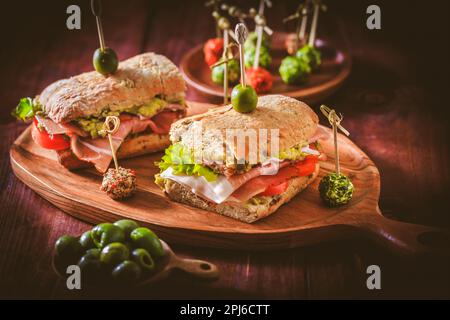 Hausgemachtes Ciabatta-Sandwich mit Guacamole, Prosciutto, Salat, Tomaten und Oliven Stockfoto