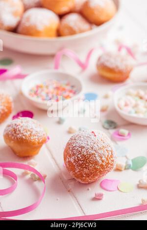 Krapfen, Berliner und Donuts mit Luftschlangen und Konfetti. Farbenfrohes Bild von Karneval, Geburtstag und Fasching Stockfoto
