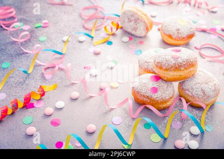 Traditioneller Berliner für Fasching und Party. Deutsch Krapfen oder Donuts mit Streamer und Konfetti. Bunte Karneval oder Geburtstag Bild Stockfoto