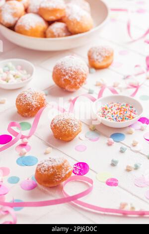 Krapfen, Berliner und Donuts mit Luftschlangen und Konfetti. Farbenfrohes Bild von Karneval, Geburtstag und Fasching Stockfoto