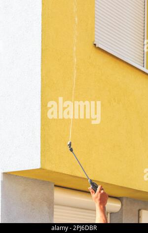 Aufbringen von Reinigungsmitteln auf schmutzige Fassade mit Hochdruckwasserstrahl Stockfoto