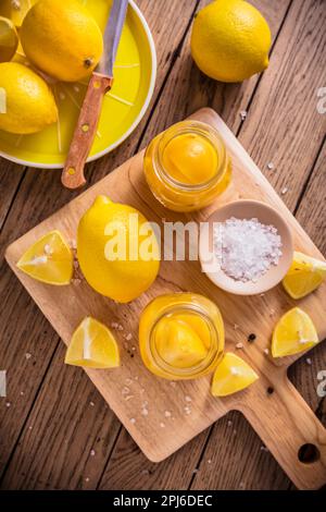 Konservierte, gesalzene Zitronenkonserven, Zitroneneingelegtes auf Holzboden. Marokkanische Küche Stockfoto