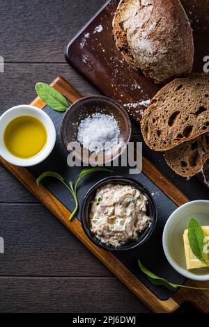 Dinkelbrot mit hausgemachtem Thunfisch-Aufstrich, Olivenöl und Salz auf Holzgrund Stockfoto