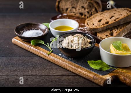Dinkelbrot mit hausgemachtem Thunfisch-Aufstrich, Olivenöl und Salz auf Holzgrund Stockfoto