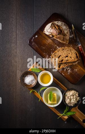 Dinkelbrot mit hausgemachtem Thunfisch-Aufstrich, Olivenöl und Salz auf Holzgrund Stockfoto